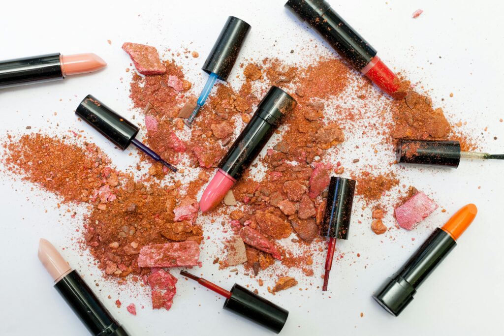 pexels-photo-1377034-1377034 Colorful scattered makeup products including lipsticks and crushed powders on a white background.
